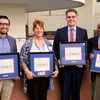 four people standing, holding awards